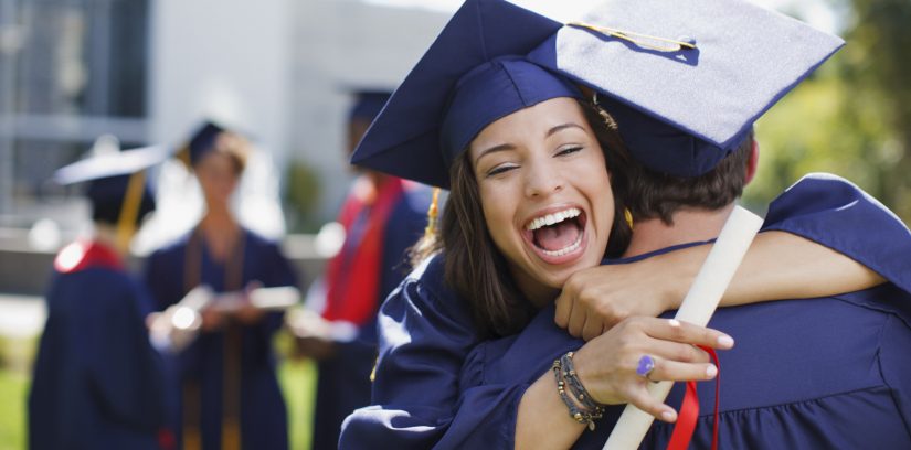 Smiling graduates hugging outdoors
